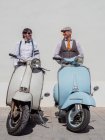 Des hipsters rêveurs d'âge moyen vêtus de vêtements à la mode avec des motos rétro penchées sur le mur par une journée ensoleillée — Photo de stock