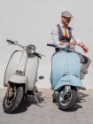 Hipster positivo de mediana edad en ropa elegante con motos retro mirando hacia otro lado en un día soleado - foto de stock