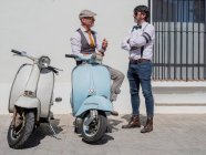 Hipsters positivos de meia-idade em roupas elegantes com motos retro conversando uns com os outros em dia ensolarado — Fotografia de Stock