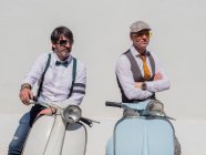 Hipsters positivos de meia-idade em roupas elegantes com motos retro olhando para longe em dia ensolarado — Fotografia de Stock