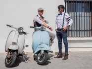 Positivi hipster di mezza età in abiti eleganti con moto retrò che distolgono lo sguardo nella giornata di sole — Foto stock