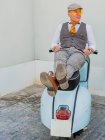 Hipster positivo de mediana edad en ropa elegante descansando en una moto retro mirando hacia otro lado en un día soleado - foto de stock
