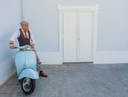 Positivo hipster di mezza età in abiti eleganti con moto retrò che distoglie lo sguardo nella giornata di sole — Foto stock
