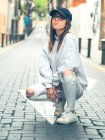 Junges modernes weibliches Modell in stilvoller lässiger Kleidung vor dem Hintergrund der Sommerstraße, die in die Kamera schaut — Stockfoto
