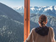 Анонімна жінка дивиться на гори з вікна — стокове фото