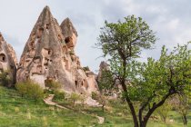 Rock houses of old city on rough mountain against cloudy sky of Cappadocia, Turkey — Stock Photo