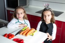 Маленькі дівчата готові почати готувати здоровий салат на кухні разом — стокове фото