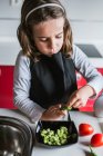 Маленька дівчинка чистить стиглі боби, готуючи здоровий салат на кухні разом — стокове фото