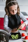 Little girl peeling ripe beans while cooking healthy salad in kitchen together — Stock Photo