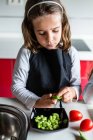 Little girl peeling ripe beans while cooking healthy salad in kitchen together — Stock Photo