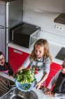 Маленькі дівчата і хлопчик Діти граються, готуючи здоровий салат на кухні разом — стокове фото