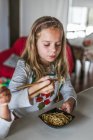 Mädchen isst leckere Nudeln mit vegetarischen Schnitzeln und Gemüse, während sie zu Hause am Tisch sitzt — Stockfoto
