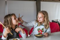 Boy and two girls eating tasty noodles with vegetarian cutlets and vegetables while sitting at table at home — Stock Photo