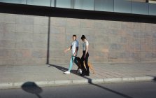 Paar spaziert und spielt mit Hund durch die Straßen der Stadt — Stockfoto