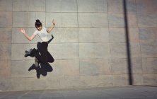 Дівчина щасливо стрибає на вулицях свого міста — стокове фото
