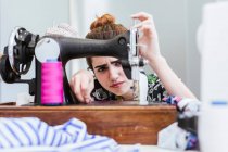 Студент-підліток практикує шиття на сучасній машині в затишній майстерні — стокове фото