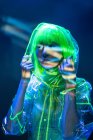 Young Asian woman in yellow wig and transparent plastic wear posing in fluorescent light — Stock Photo