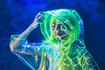 Молода Азіатська жінка в жовтому перуці і прозорий пластиковий знос постановки в флуоресцентне світло — стокове фото