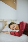 Jovem mulher bonita de pijama sorrindo enquanto dormia na cama no quarto — Fotografia de Stock