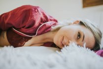 Feliz jovem bonita mulher de pijama sorrindo na cama no quarto — Fotografia de Stock