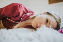 Sinnliche junge hübsche Frau im Schlafanzug lächelnd auf dem Bett im Schlafzimmer — Stockfoto