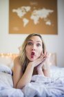 Young cheerful woman in underwear grimacing in bed — Stock Photo