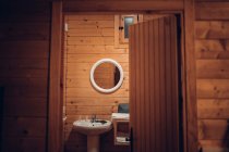 Затишна ванна кімната в дерев'яному будинку з відкритими дверима і сучасним обладнанням — стокове фото