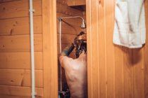 Homme prenant une douche dans la salle de bain en bois — Photo de stock