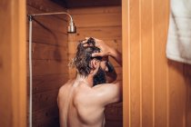 Hombre tomando ducha en baño de madera - foto de stock
