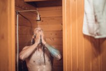 Homme prenant une douche dans la salle de bain en bois — Photo de stock