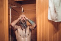Mann duscht im Holzbadezimmer — Stockfoto
