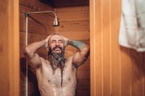 Mann duscht im Holzbadezimmer — Stockfoto