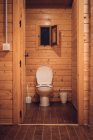 Bathroom in wooden house with opened door — Stock Photo