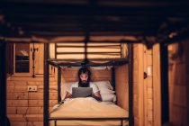 Чоловік використовує ноутбук у сільському двоярусному ліжку — стокове фото