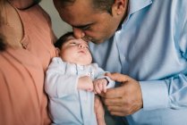 Happy young mother holding newborn baby and father standing to them at home — Stock Photo