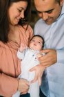 Glückliche Eltern, während sie weinendes Baby zu Hause halten und umarmen — Stockfoto