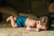 Cute little innocent newborn baby in back lying on sofa at home — Stock Photo