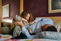 Dad having fun with happy daughter while lying on bed — Stock Photo