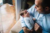Padre abrazando lindo bebé mirando hacia otro lado en casa - foto de stock