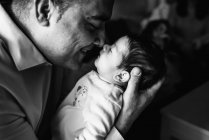 Pai abraçando bonito pequeno bebê olhando para longe em casa — Fotografia de Stock