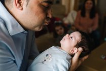 Vater umarmt niedliches kleines Baby, das zu Hause wegschaut — Stockfoto