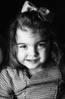 Kleines hübsches Mädchen blickt auf dunklem Hintergrund in die Kamera — Stockfoto