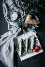 Salted anchovies placed on heap of rosemary sprigs near fabric napkin with olive branches and fresh bread — Stock Photo