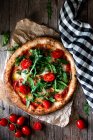 Deliciosa pizza com tomates, rúcula e mussarela em fundo de madeira rústica — Fotografia de Stock