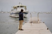 Visão traseira do homem adulto anônimo em roupa casual passar tempo com Bulldog francês no cais de madeira perto do mar — Fotografia de Stock