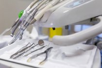 Ferramentas de aço dentista como afiado, raspador, escultor, broca e espelho na bandeja na mesa no armário dentário na clínica — Fotografia de Stock