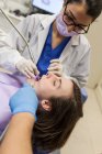 Dentista mulher que atende um paciente — Fotografia de Stock