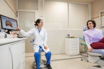 Dentista femenino asesorando a la paciente y mostrando su tratamiento - foto de stock