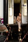 Soldado feminino forte olhando para a câmera enquanto sentado na porta do veículo militar grungy no campo — Fotografia de Stock