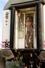 Forte soldato donna guardando la fotocamera mentre in piedi sulla porta di grungy veicolo militare in campagna — Foto stock
